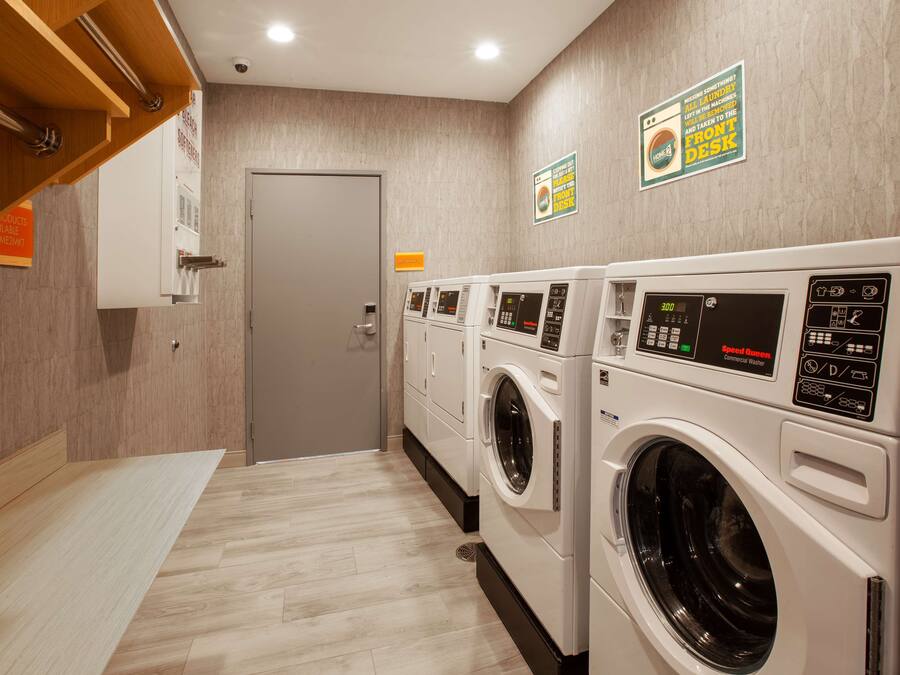 A laundry area with multiple washing machines, a door, and a sign indicating a front desk.