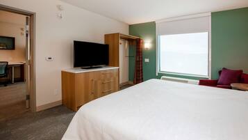 A hotel room with a bed, a television, a wardrobe, and a window with a view.
