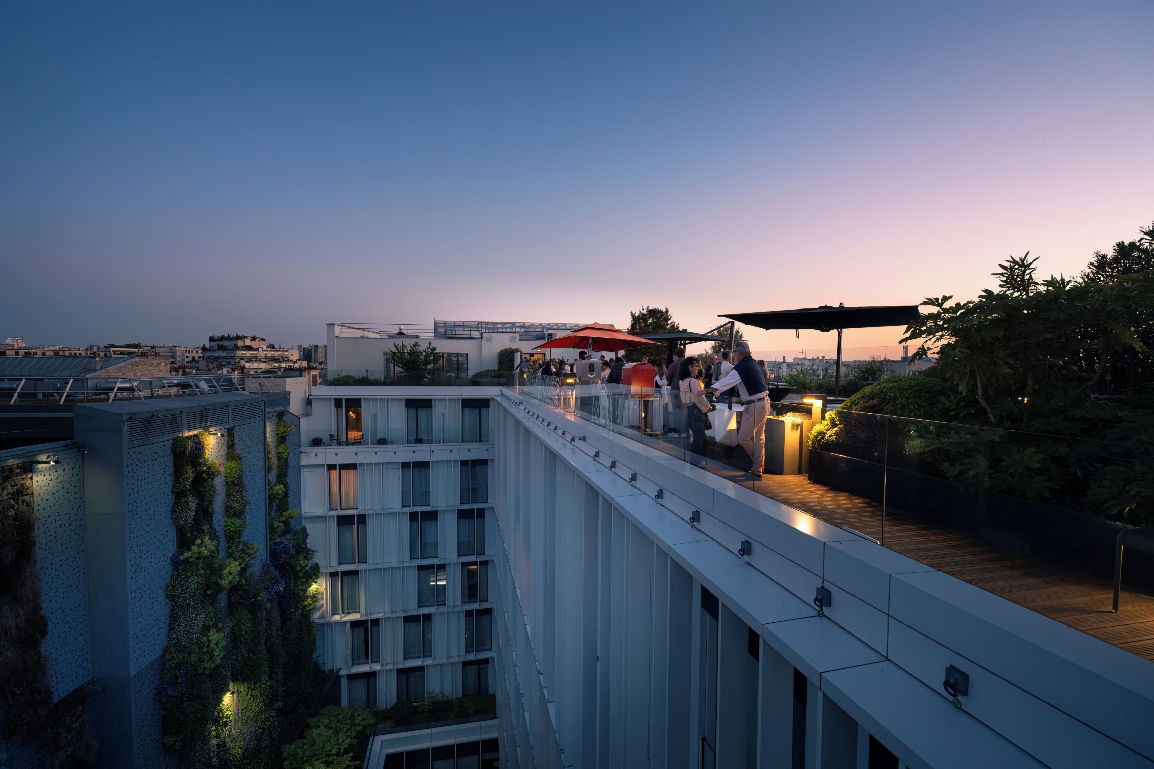 A modern building with a rooftop terrace, a view of the city, and a balcony with a railing.