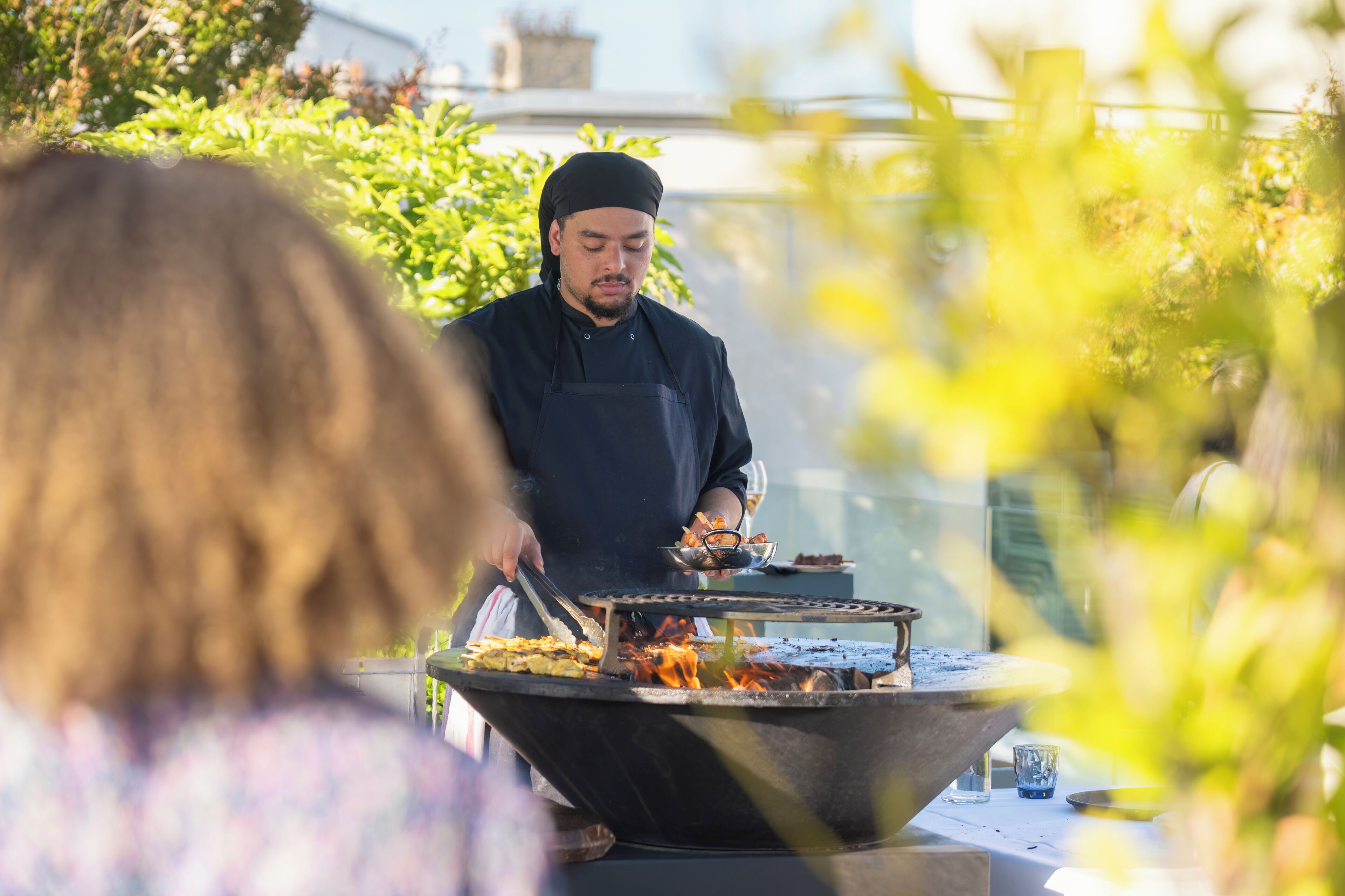A person cooking outdoors with a large grill.