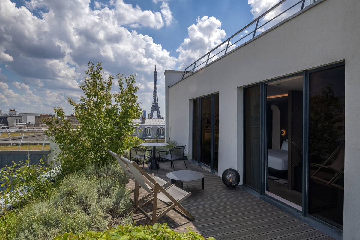 A modern rooftop terrace with a view of the Eiffel Tower, a dining table, and a lounge area.