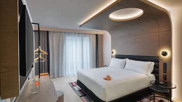 Une chambre d’hôtel moderne dotée d’un grand lit, d’une télévision à écran plat, d’un bureau avec un bocal en verre et d’un design de plafond original.
