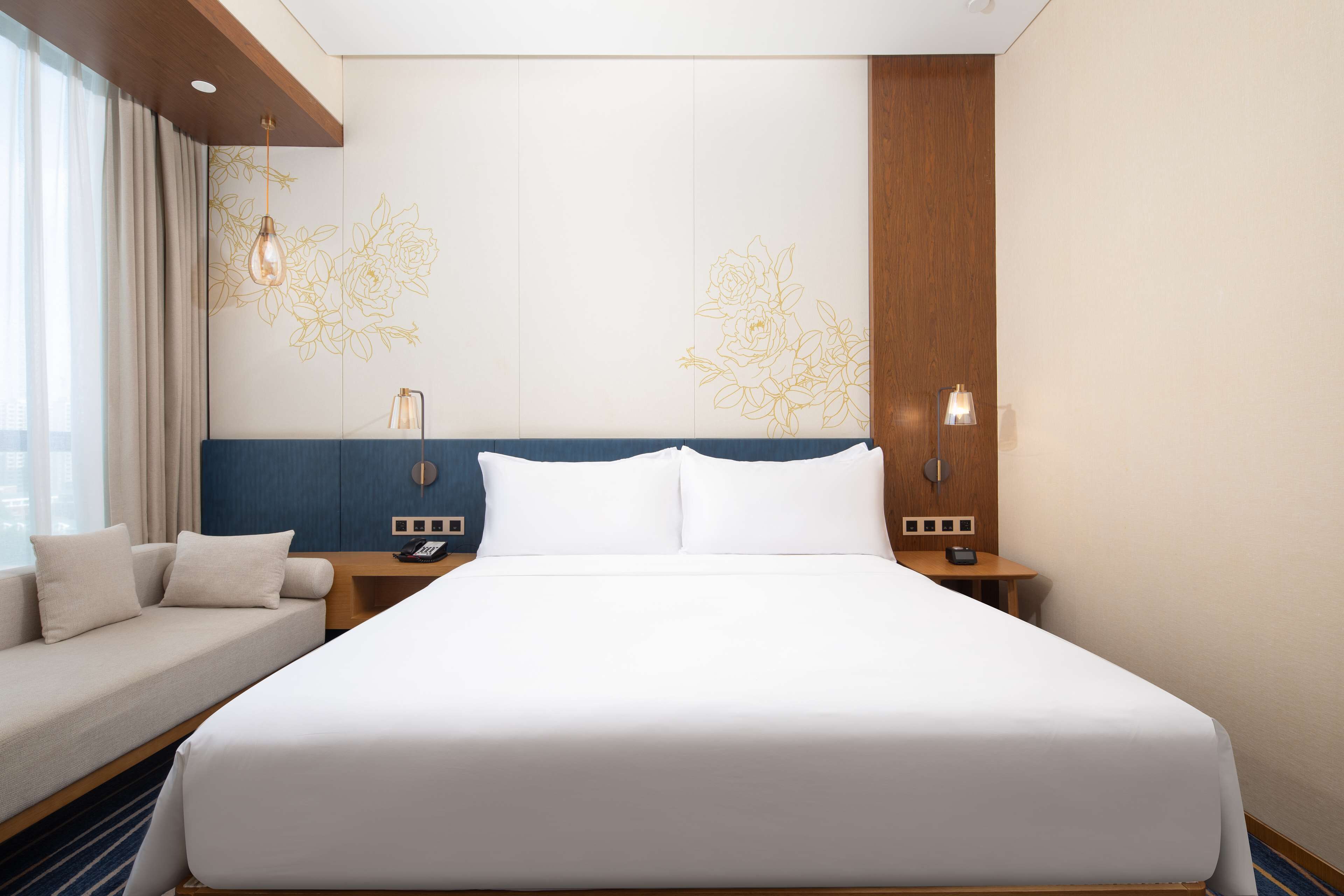 Una habitación de hotel con una cama grande, un sofá, un escritorio y una mesita de noche.