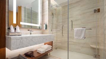 A modern bathroom with a glass-enclosed shower, marble sink, and wooden vanity.