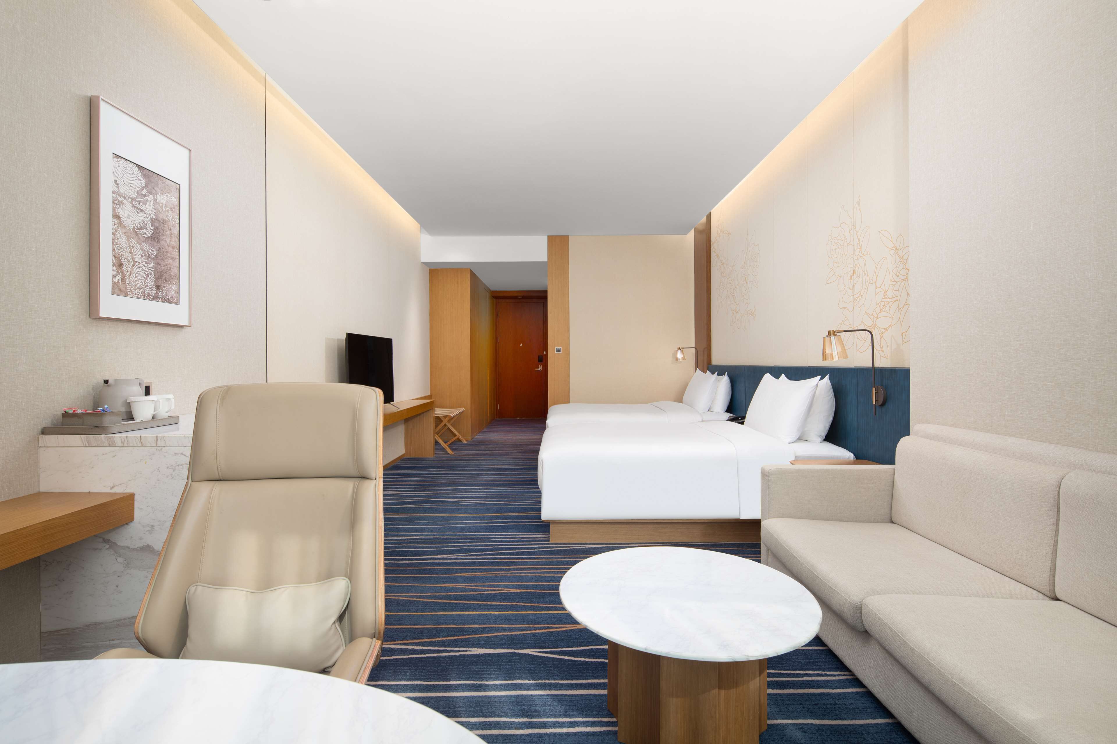 Una habitación de hotel con cama, sofá, escritorio y una silla, además de una mesita.