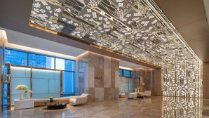 A modern lobby with a reflective floor, seating areas, and a decorative ceiling. - Hilton Garden Inn Zibo Zhangdian (Zibo)