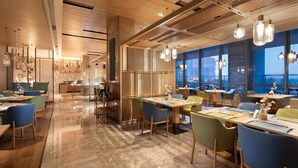 A modern restaurant interior with wooden ceiling panels, large windows, and contemporary lighting fixtures. - Hilton Garden Inn Zibo Zhangdian (Zibo)