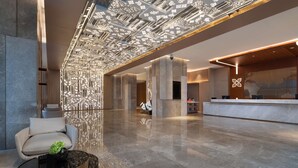 A modern lobby with a reflective floor, a reception desk, and a patterned ceiling. - Hilton Garden Inn Zibo Zhangdian (Zibo)