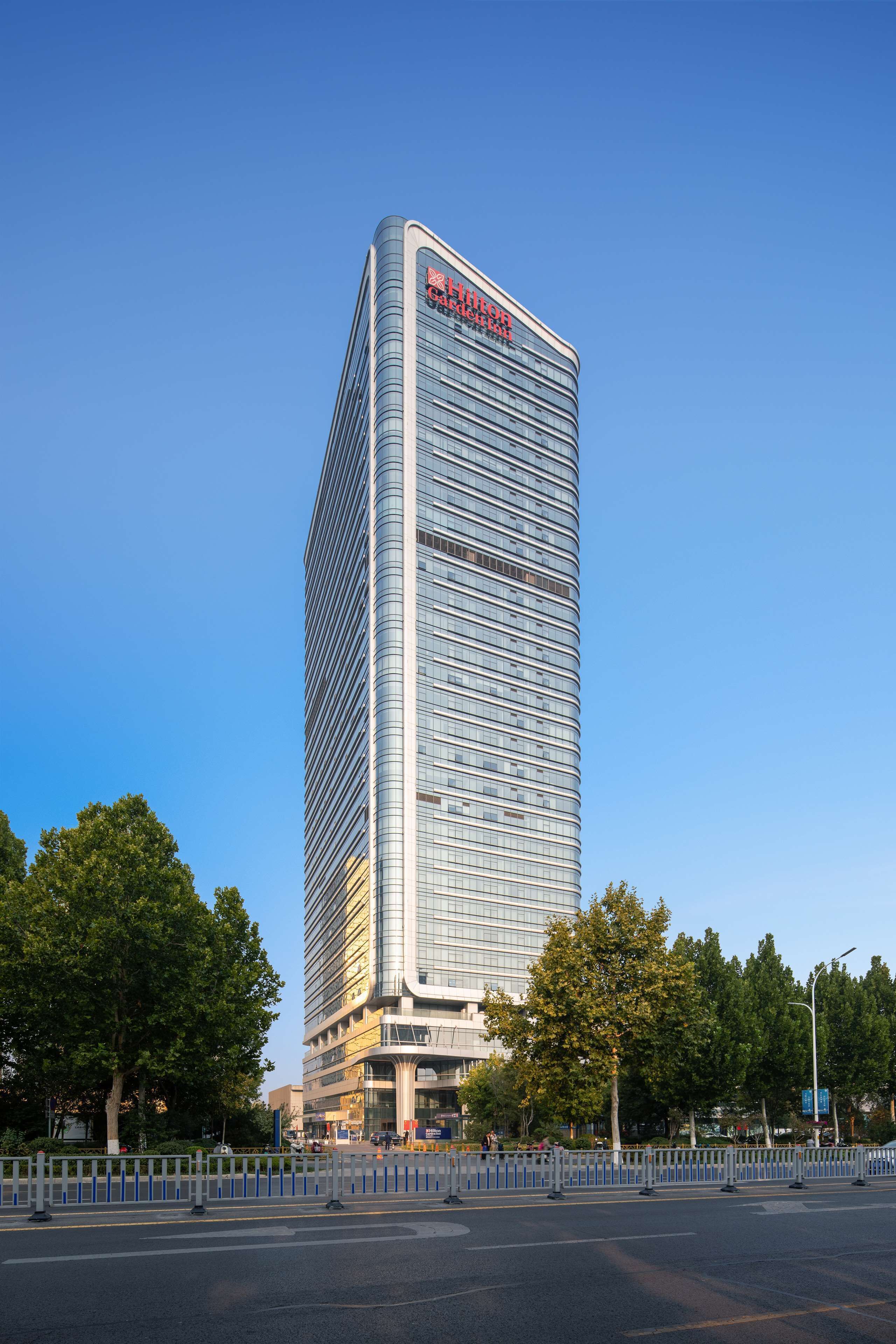 A tall, modern skyscraper with a curved glass facade and a prominent logo at the top.