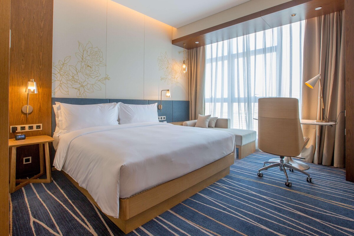 A hotel room with a large bed, bedside tables, a desk, and a chair.