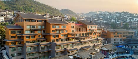 Un hôtel moderne, doté de plusieurs étages, avec des bâtiments de style traditionnel en arrière-plan.