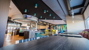 Una bolera con zona de bar, taburetes coloridos y un diseño moderno de techo.