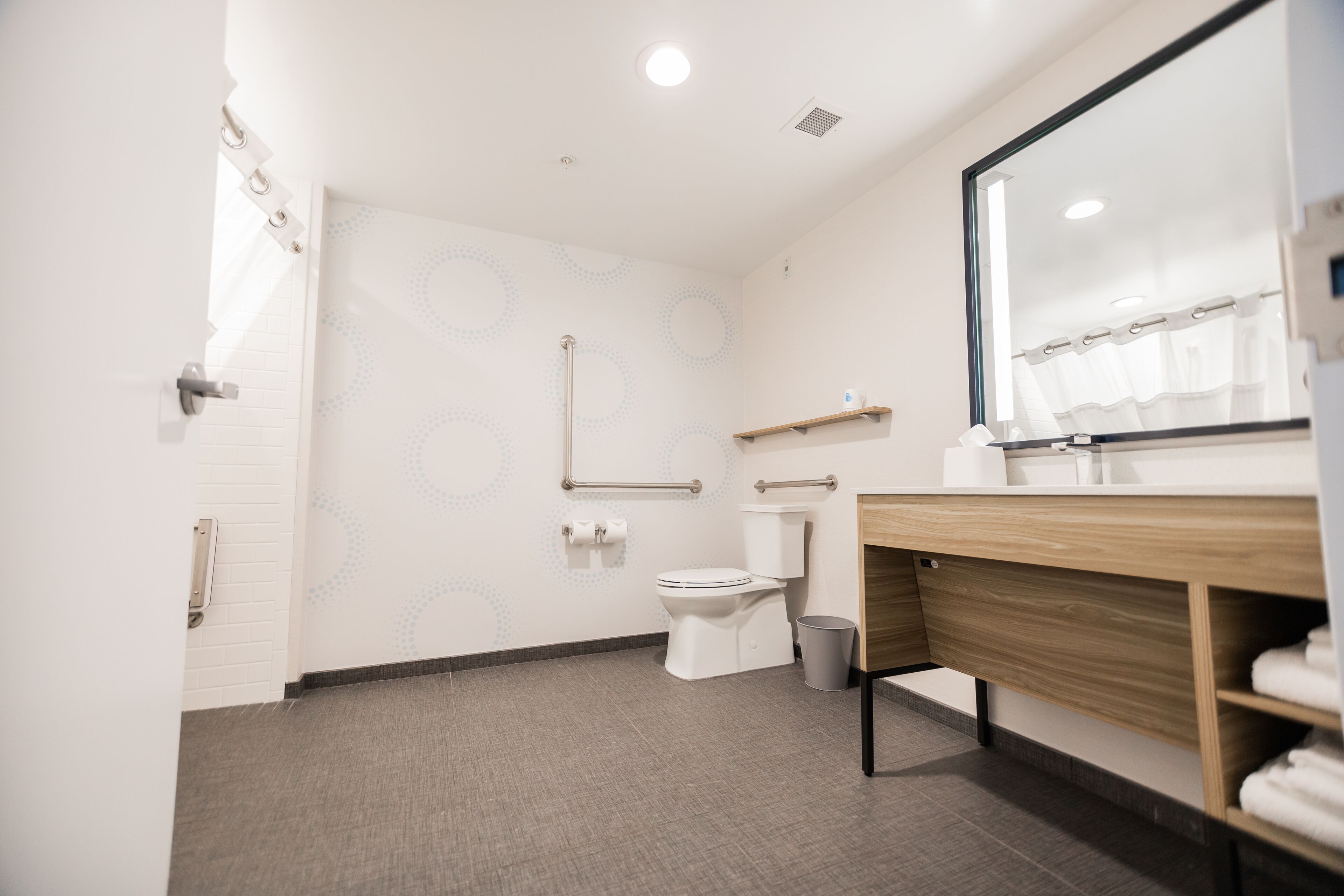 A modern bathroom with a toilet, bidet, and a wooden vanity with a mirror.