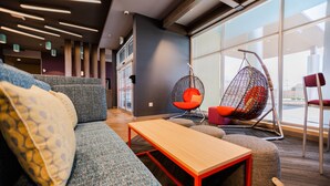 Un área de estar moderna con un sofá, una silla colgante y una mesa de madera.