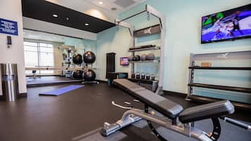 A gym with exercise equipment, a television, and a mirror.