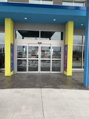 Entrada de hotel con puertas de vidrio y fachada azul y amarilla.