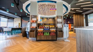 Zona de mercado abierta las 24 horas con opciones de bocadillos y bebidas, un espacio con asientos y una barra.