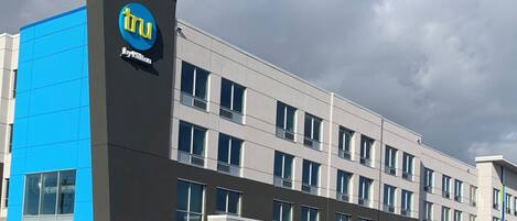 A modern building with a prominent blue and grey facade, featuring a large logo on the left side.