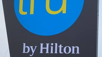 Un letrero con el logotipo "tru by Hilton" sobre un fondo oscuro.