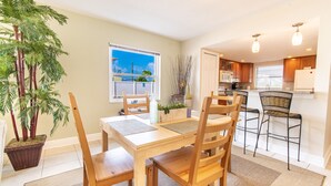 A dining area with a wooden table and chairs, a potted plant, and a view of the outside. - Maximo Marina Condo • Heated pool, Near Pass-a-Grille, Downtown & Eckerd (St. Petersburg)