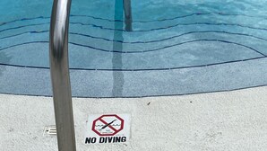 A swimming pool with a metal ladder and a 'NO DIVING' sign. - Maximo Marina Condo • Heated pool, Near Pass-a-Grille, Downtown & Eckerd (St. Petersburg)