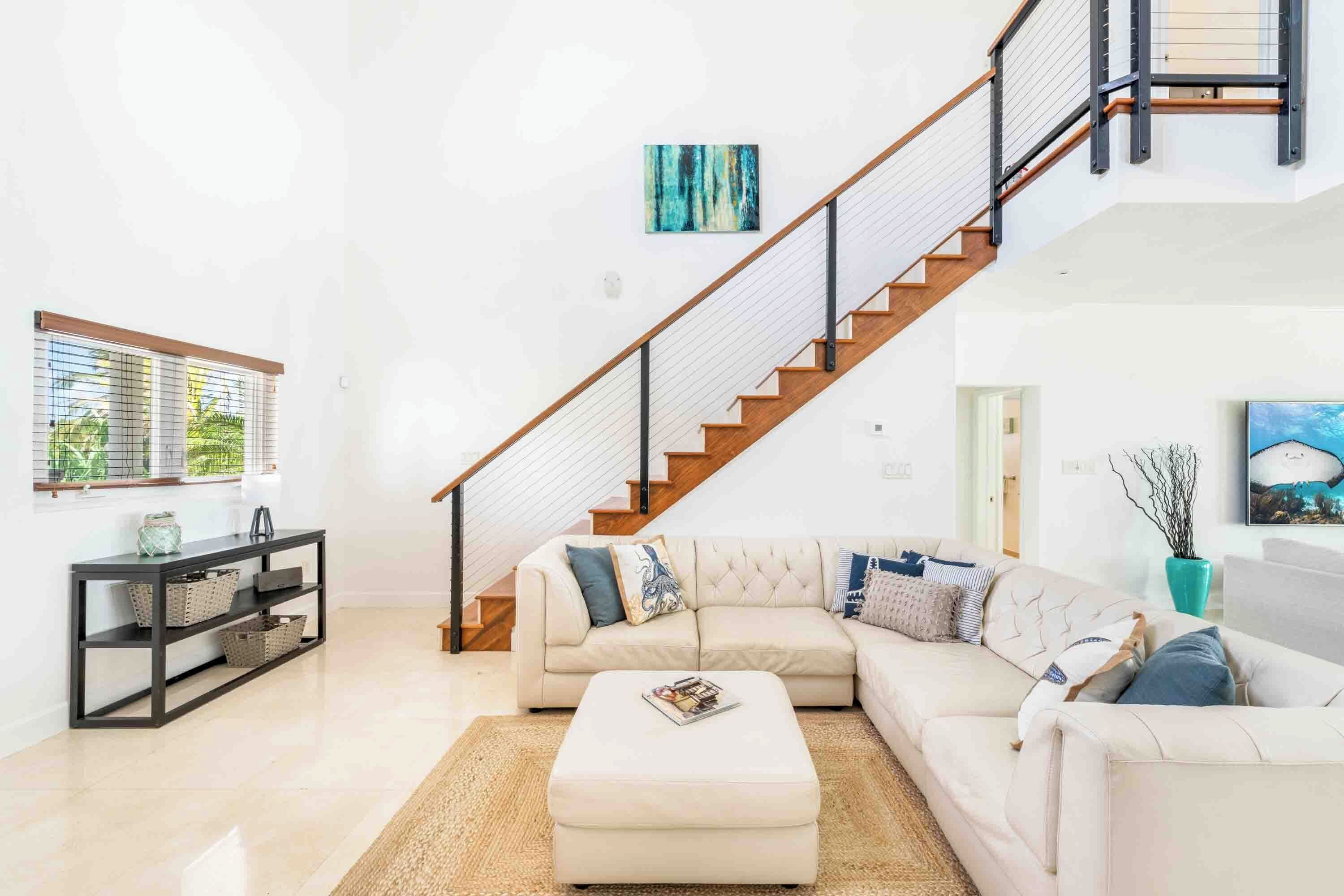 A modern living room with a staircase, a sectional sofa, a coffee table, and a console table with baskets.