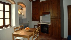 A kitchen with wooden cabinets, a dining table with chairs, and a window with a view.