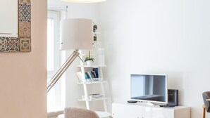 A modern living room with a white sofa, a beige armchair, a TV, and a bookshelf. - FLH Best of Principe Real Liberdade in the Heart o (Lisboa ciudad)