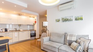A modern kitchen with white cabinets, a dining area with a table and chairs, and a living room with a sofa and a lamp. - FLH Best of Principe Real Liberdade in the Heart o (Lisboa ciudad)