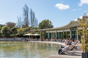A waterfront area with a pool, lounge chairs, and a covered seating area.