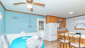 A kitchen with wooden cabinets, a white refrigerator, and a bar area with two stools. - Lakeside Retreat (Caseville)