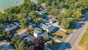 An aerial view of a residential area with houses, a road, and a body of water. - Lakeside Retreat (Caseville)