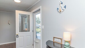 A hallway with a white door, a small table with a lamp, and a sign that reads "Welcome Home." - Lakeside Retreat (Caseville)