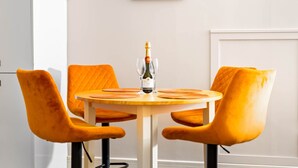 A round table with two orange chairs, a bottle of wine, and two glasses on it.