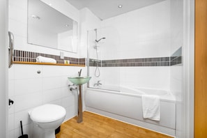 Un baño moderno con lavamanos de vidrio, inodoro, ducha y bañera.