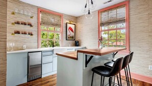 A modern kitchen with a wooden countertop, bar stools, and a stainless steel refrigerator. - Grand 10BR Charleston Home with Speakeasy Bar, Gym (Charleston)