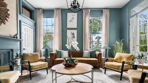 A spacious living room with a large window, a sofa set, a coffee table, and a fireplace. - Grand 10BR Charleston Home with Speakeasy Bar, Gym (Charleston)
