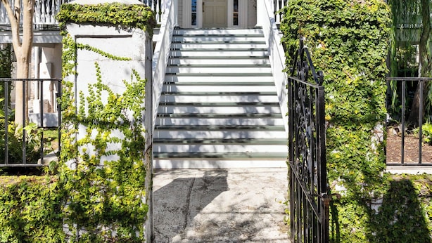 A white colonial-style house with a front porch, steps, and a gated entrance. - Grand 10BR Charleston Home with Speakeasy Bar, Gym (Charleston)