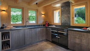 Une cuisine moderne avec des meubles en bois, une grande cuisinière et une fenêtre donnant sur un espace verdoyant.
