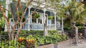 Une maison avec un porche, un vélo et une clôture ornée de plantes.