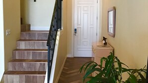 Un escalier avec des marches en bois et une rampe noire menant à une porte blanche.