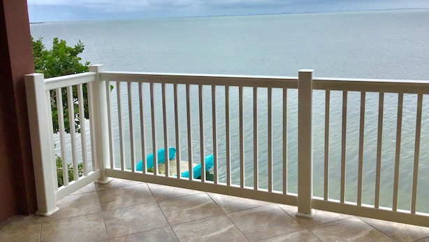 Un balcon doté d’une balustrade blanche donnant sur une étendue d’eau.