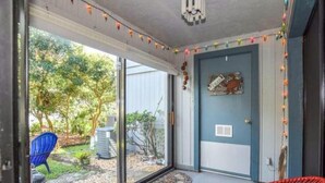 Una habitación con una puerta corrediza de vidrio que da a un jardín, una silla azul y una puerta con un rótulo que dice 'CLEAN'.