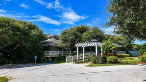 Un espacio exterior cubierto con una pérgola, una escalera y un edificio al fondo.