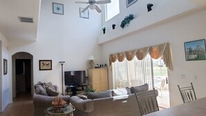 A spacious living room with a sofa, a television, and a dining area.