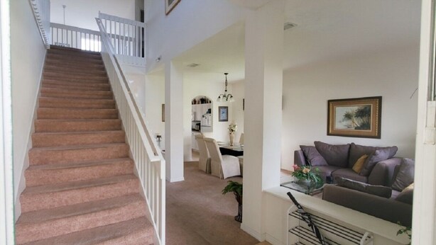 A staircase leading to a second floor, a living area with a sofa and a dining area in the background.