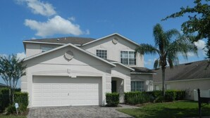 A two-story house with a garage, a driveway, and a well-maintained lawn.