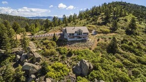 A house surrounded by a forested hillside with a clear view of the surrounding landscape.
