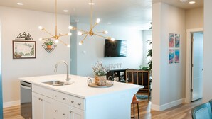 A modern kitchen with a central island, a dishwasher, and a dining area with a bar stool. - Adventure Awaits in Southern Utah | Pool + Resort Style Amenities | Come Adventure with Family! (Washington)