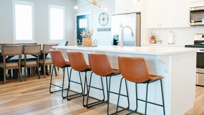 A modern kitchen with a central island, bar stools, and stainless steel appliances. - Adventure Awaits in Southern Utah | Pool + Resort Style Amenities | Come Adventure with Family! (Washington)